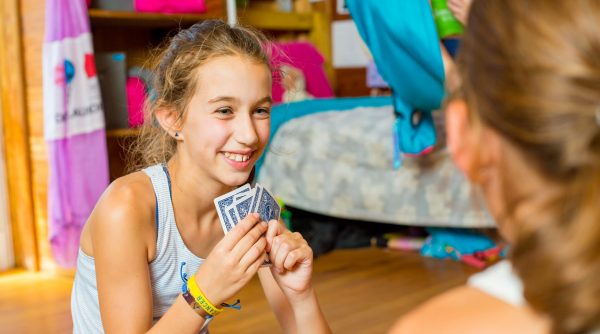 Young camper playing cards in bunk