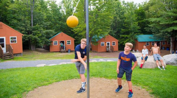 Campers playing tetherball by bunks